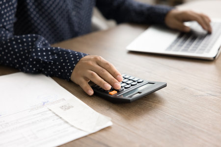 Female managing personal finances using laptop and calculator, track expenses incomes, savings, and...