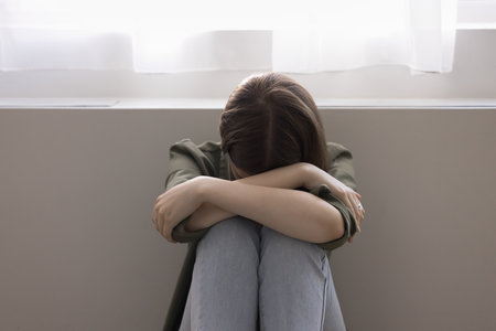 Unhappy lonely adolescent girl suffers from bullying at school, hiding face, feels depressed, hopeless, offended, think about personal problem, worried about lack of communication. Teenage concernsの写真素材