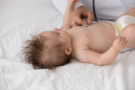 Unknown doctor holds stethoscope listens newborn heart beat, close up. Paediatrician check breath, examining lungs of infant during regular nurse visit at home. Health-care, medical check-up conceptの写真素材