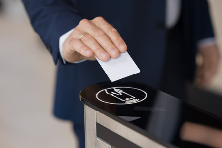 Hand of business man holding electronic keycard at sensor control keypad, using security system, applying identity badge for gate unlock at office entrance, using business security system. Close upの写真素材