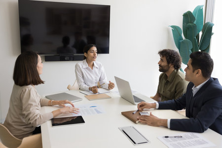 Inspired Indian female professional business trainer motivation speaker lead coaching session talk to interested trainees group. Young woman boss discuss plan idea with multiethnic corporate employeesの写真素材