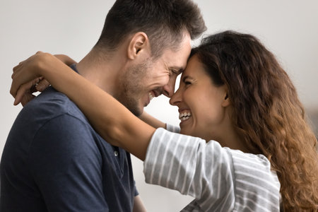 Cheerful attractive couple in love hugging with faces touch, talking, laughing, dancing together at...