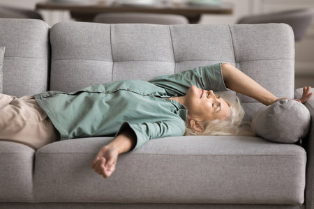 Tired woman felt asleep on couch, after hard-working day or sleepless night, flopped down on sofa looks like squeezed lemon, drained, need rest for restoring. Overworking, exhaustion, lack of energyの写真素材