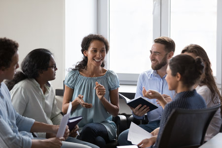 Happy diverse addicts sitting on chairs in circle, talking on group therapy meeting, discussing...