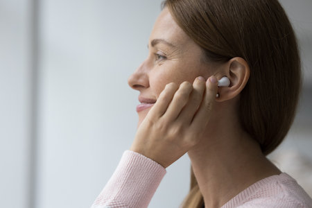 Beautiful smiling woman enjoy quality sound and favourite song through wireless earphones, profile...