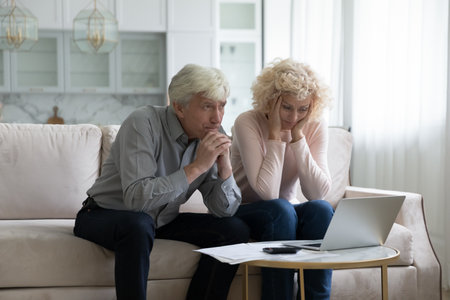 Concerned mature husband and wife frustrated about overspending family budget, money problems,...