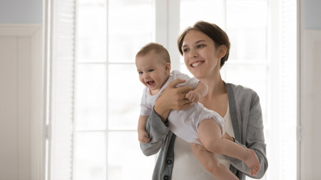 Mother and baby bonding. Happy excited little infant kid feel healthy comfortable having dry skin in diaper sit on caring mommy babysitter hands enjoy warm embraces of loving parent nanny. Copy spaceの写真素材