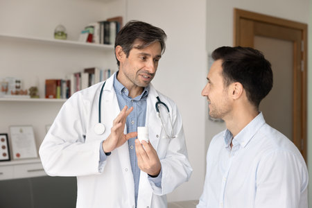 Male doctor showing pills bottle to patient, prescribing vitamins, food supplement, painkiller, giving drugs prescription after medical checkup, treatment recommendation to manの写真素材