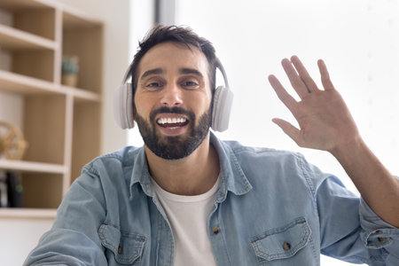 Webcam view, young Latin man wear wireless headphones greeting client, start videocall meeting...