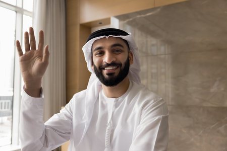 Successful Arabian man entrepreneur wear traditional kandura greeting partner start video conference...