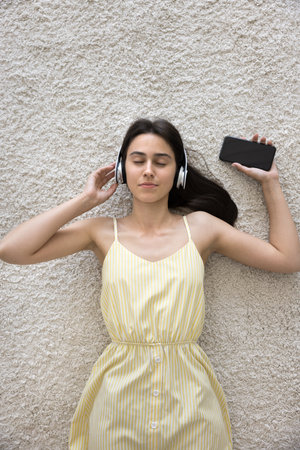 Meditating and chilling out. View from above carefree young girl in wireless earphones lying on fluffy carpet with closed eyes relieve stress relax listen to calm music from phone playlist. Copy spaceの写真素材