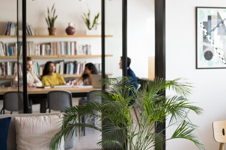 Blurred shot diverse students engaged in peer learning prepare for exam work on group project at library desk. Comfy modern coworking area with wifi access paper digital materials concept. Copy spaceの写真素材