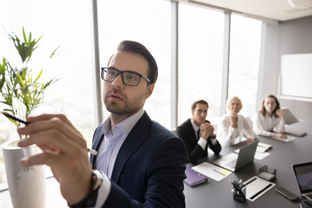 Corporate education in business tutoring. Focused coach trainer mentor lead seminar workshop for businesspeople team use pencil to correct mark write information on board with paper graphs. Copy spaceの写真素材