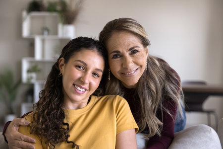 Close up portrait of beautiful women posing or camera in living room, showing understanding between two different generations, share support, feeling unconditional love. Mother and daughter connectionの写真素材