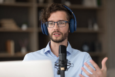 Inspired male zoomer in wireless headset motivational speaker business trainer teacher presenting speech idea on virtual conference talking to class tutoring student remotely using microphone notebook.の写真素材