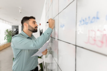 Serious Latin project leader man writing on white Kanban scrum management board, holding documents, preparing project presentation, working on tasking. White board close upの写真素材