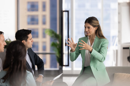 Excited Latin business leader woman holding brainstorming meeting, sharing creative ideas for project, talking to listening team, explaining work task. Coach training focus groupの写真素材