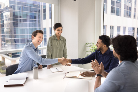 Motivated team members handshake, start or accomplish formal meeting in conference room, concluding successful agreement or partnership, express mutual respect, thanking for professional collaborationの写真素材