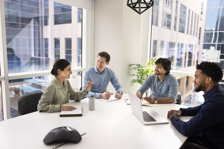 Professional team listening Indian female colleague share point, vision and creative solution. Businesspeople engaged in collaboration or deal discussion, reviewing project revenue and profitabilityの写真素材