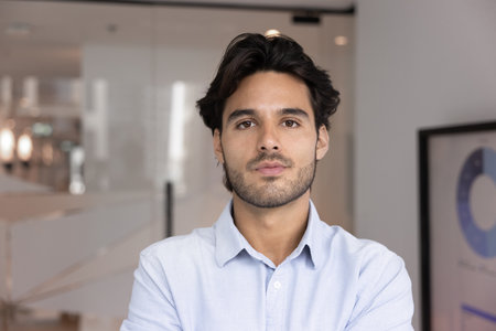 Head shot portrait of skilled Hispanic businessman, project manager looking at camera with confident and serious expression, exuding competence, professionalism, leadership in business, close up photoの写真素材