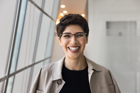 Head shot of cheerful Armenian businesslady, look at camera with joyful expression, feel satisfied with career growth or promotion, exude professionalism, competence and reliability. Business portraitの写真素材