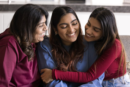 Family bonding and love. Happy older mom grown sister cuddle smiling young woman sitting on sofa...
