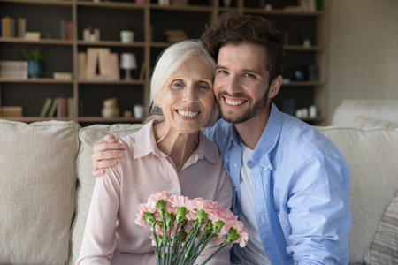 Happy Mothers Day. Family portrait affectionate caring adult son look at camera hug shoulders of...