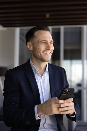 Happy handsome Hispanic business professional man typing on cellphone, chatting on Internet, looking...