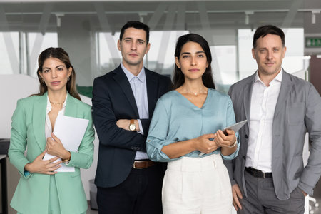 Portrait of diverse corporate teammates, business leaders standing indoors, posing in office,...