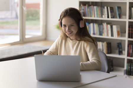 Engaged in remote learning. Focused teenage female student pupil study at distance use notebook web...