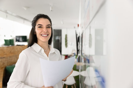 Latina professional woman, project coordinator or female office manager standing in creative...