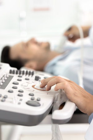 Ultrasonography. Close up doctor hand navigating diagnostic interface of ultrasound computer machine examining male patient lying on couch on background. Cancer prevention using modern tech conceptの写真素材