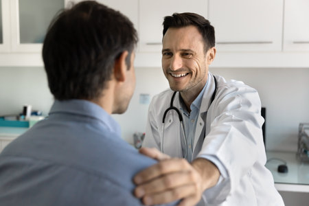 Supportive hand of trusted doctor. Kind smiling medical professional gently put hand on shoulder of...