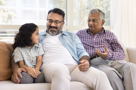 Positive father and Indian granddad babysit adorable kid girl. Sweet child and men of three family...