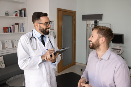GP making notes in history card, consulting client, asks about condition during his visit at clinic office. Healthcare services, insurance, friendly communication and trust between doctor and patientの写真素材