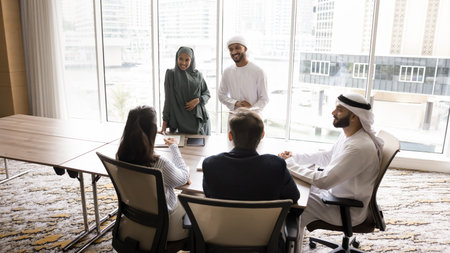 Round table meeting. Young diverse Muslim couple business trainers in ethnic wear gather multicultural corporate staff for team building activity hold informal conversation at boardroom. Copy spaceの写真素材