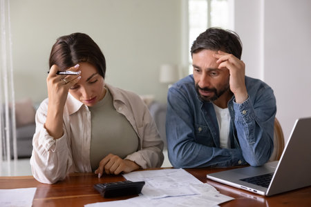 Financial stress pressure. Troubled concerned family couple distressed with home accounting results review papers confused by loan credit debt business bankruptcy risk frustrated with overdue tax feesの写真素材