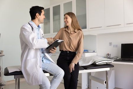 Happy young woman shake hands with male doctor, finalizing professional medical consultation or check-up in clinic office. Successful treatment plan discussion, agreement, trust between GP and patientの写真素材