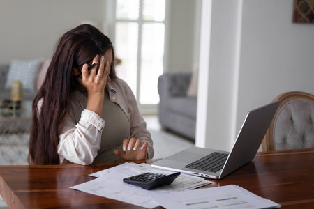 Home accounting challenge. Confused worried young female homeowner entrepreneur deal with money problem working on bills with calculator laptop overwhelmed by bankruptcy debt manage financial crisisの写真素材