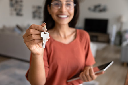 Bunch of key in female realtor hand close up. Happy real estate agent woman in glasses offering...