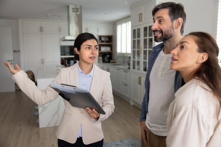 Property tour presentation. Confident female real estate professional agent consultant show realty object modern house apartment interior to interested couple explain lease purchase mortgage detailsの写真素材