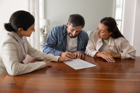 Contract signing. Smiling businesswoman real estate broker insurer bank manager watch glad clients family couple putting signature on official paper document close deal on life insurance housing loanの写真素材