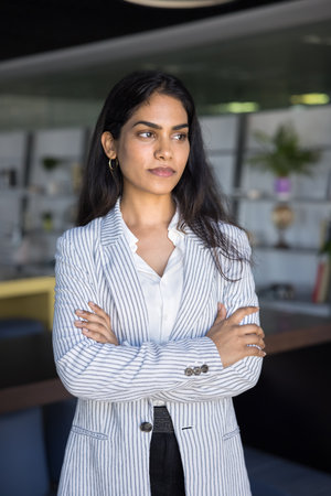 Ambitious and successful. Portrait confident young businesswoman ceo executive standing in modern office looking aside visualizing future of her business planning career growth think about professionの写真素材
