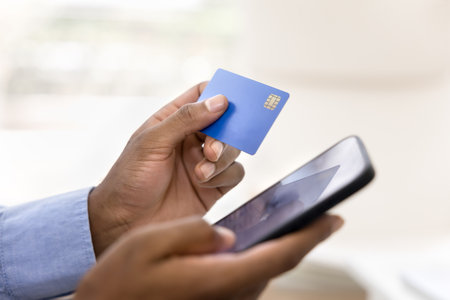 Close up, male hands holds card and smartphone, pay bills online using secure banking system, do...