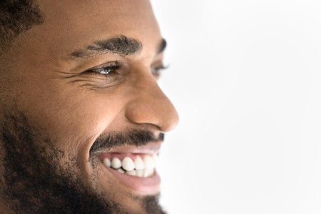 Close up happy African man laughing, looking away, cropped face view on white studio wall background, copy space.の写真素材