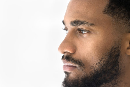Side profile view face of serious handsome African man having attractive appearance, trimmed well-groomed beard, looking straight, copy space white background. Male beauty, treatment and procedure adの写真素材