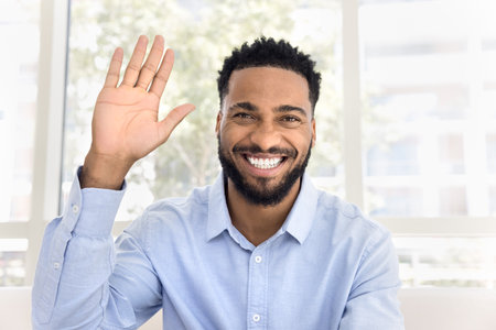 Head shot portrait of happy young 30s African man welcoming friend, start on-line conversation, enjoy remote communication using videocall application. Social media icon, influencer profile pictureの写真素材