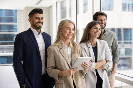 Diverse business team of happy young businesspeople with female leader standing together in office,...