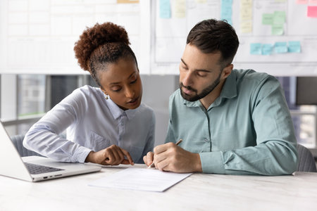 Making agreement. Confident young female legal advisor saleswoman finalize business deal with millennial businessman guide customer through signing paper contract after approval of terms conditionsの写真素材