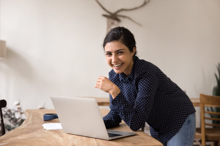 Successful creator. Portrait happy joyful millennial female influencer stand at workplace looking at camera using notebook to prepare blog post video script creating commercial social media contentの写真素材